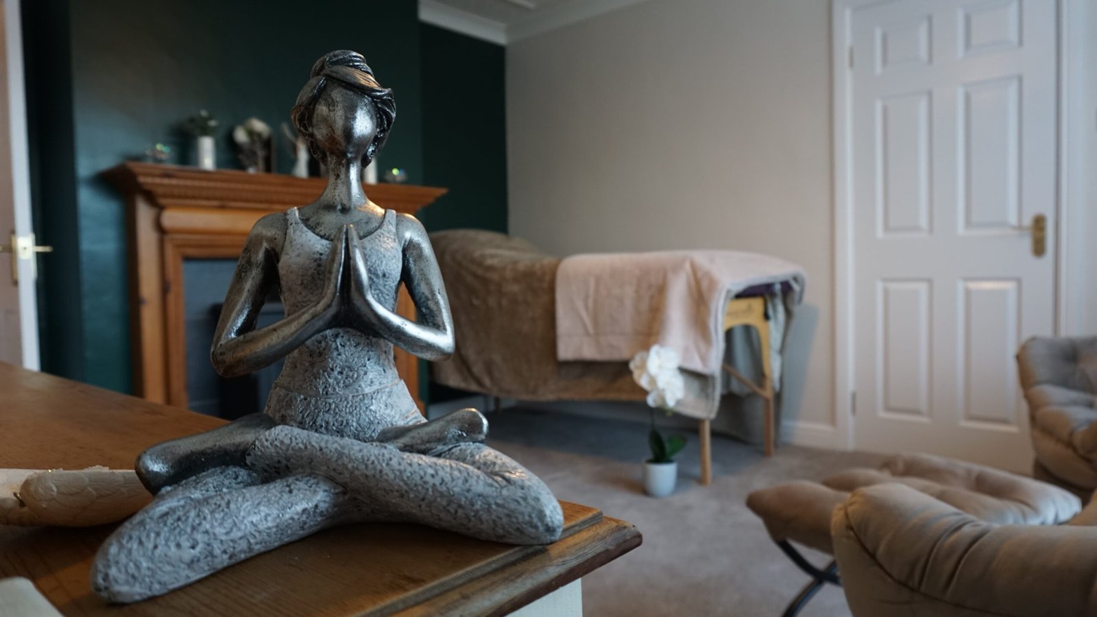 Reiki practitioner room with a table and small figurine with crossed arms and legs